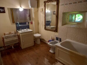 Ein Badezimmer mit Holzboden, einem weißen Waschbecken, einer Toilette und einer Badewanne.