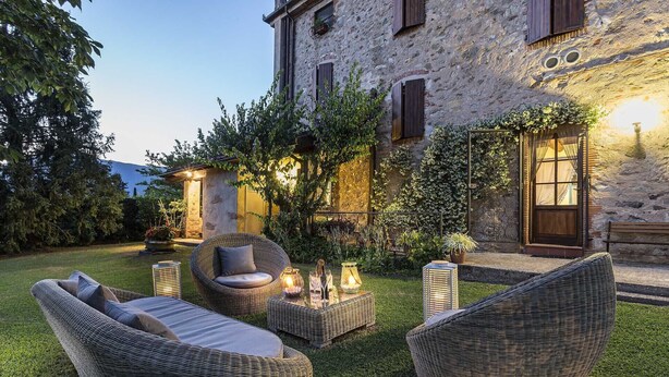 A stone building with a garden patio featuring wicker furniture and outdoor lighting. - Tuscan Fairytale Family Villa close to Beaches and Lucca (Camaiore)