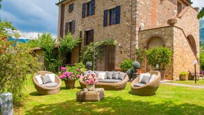 A stone building with a garden patio featuring wicker furniture and potted plants. - Tuscan Fairytale Family Villa close to Beaches and Lucca (Camaiore)