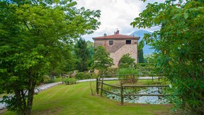 A stone building with a red roof, surrounded by lush greenery and a pond. - Tuscan Fairytale Family Villa close to Beaches and Lucca (Camaiore)