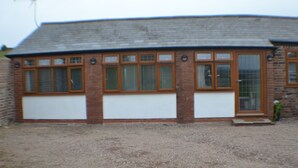 A building with a brick facade, large windows, and a gravel driveway. - Why book a room when you can have a suite (Wootton)