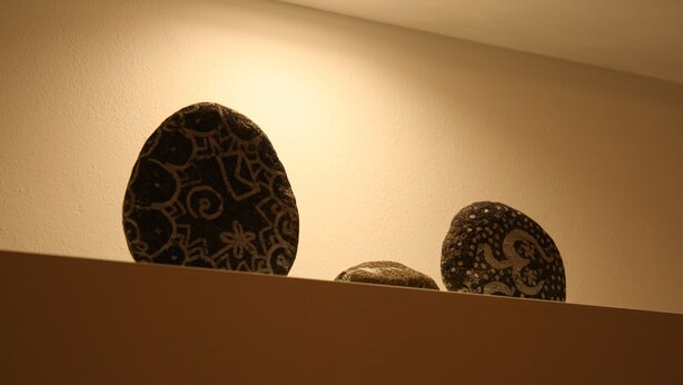 Tres piedras decorativas sobre una repisa frente a una pared lisa.