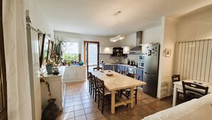 A compact kitchen with a dining area, featuring a wooden table, chairs, a refrigerator, and a stove.