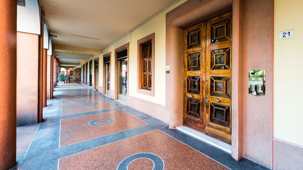 A hotel corridor with a long hallway, wooden doors, and a number 21 sign.