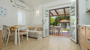 A room with a dining area, a sofa, and a sliding glass door leading to an outdoor patio. - Villa with parking and veranda, 900 m from the beach - San Teodoro (San Teodoro)