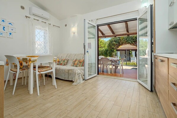 A room with a dining area, a sofa, and a sliding glass door leading to an outdoor patio.