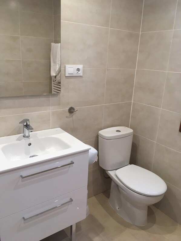 Une salle de bain avec un lavabo blanc, des toilettes et un miroir.
