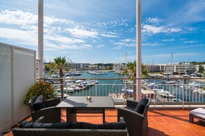 A terrace with wicker furniture, a table, and a view of a marina with boats. - Contemporary Apartment in heart of Marina, New Decor (Lagos)