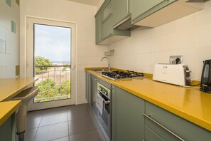 A compact kitchen with a yellow countertop, a built-in oven, a gas stove, and a coffee maker.