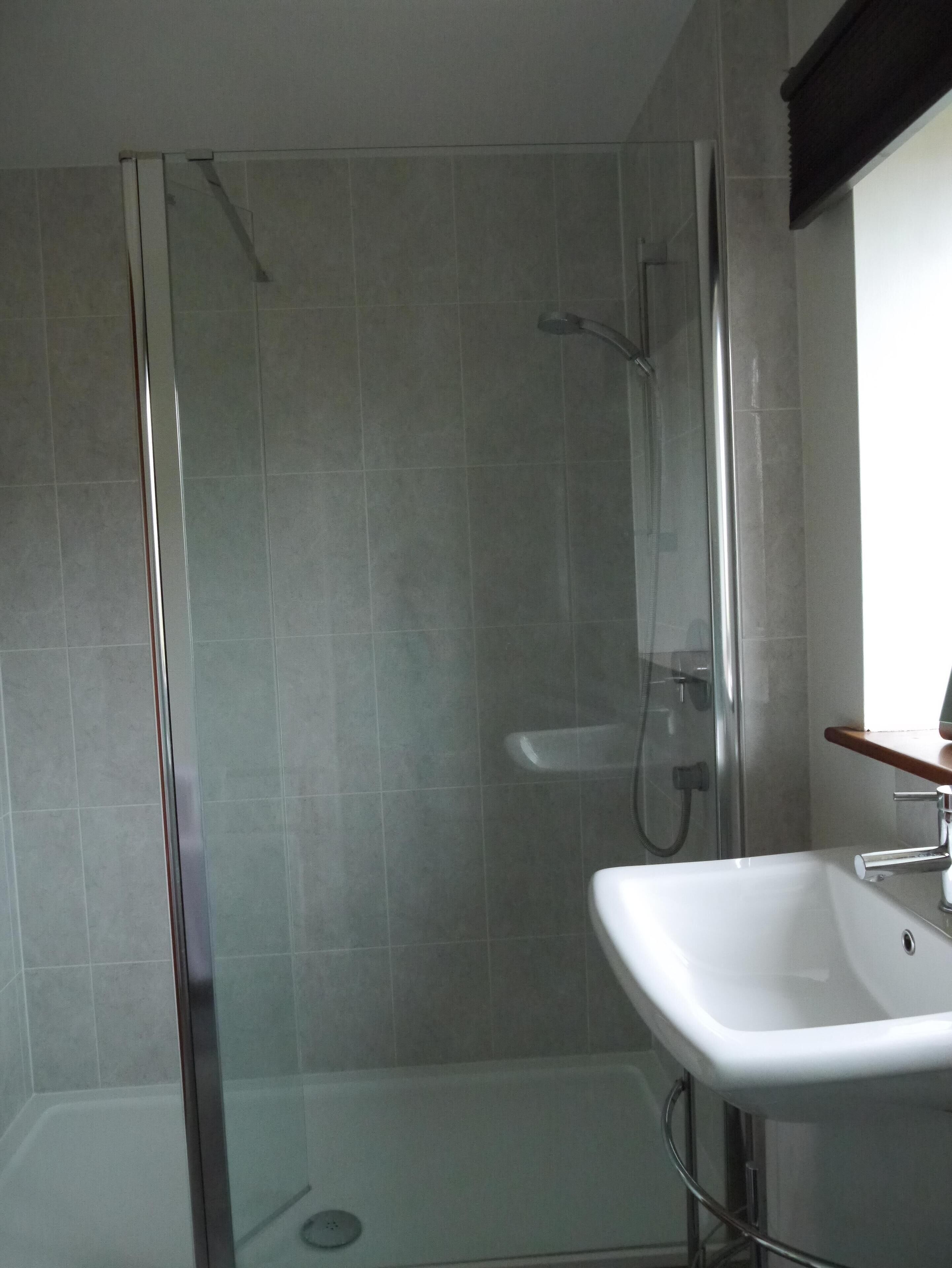 A modern bathroom with a glass-enclosed shower, a white sink, and a wooden countertop.
