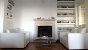 A living room with a fireplace, white sofas, and shelves with glassware. - LE QUERCE - Villa with spectacular sea view and swimming pool (Maratea)