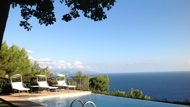 An infinity pool with two metal ladders, surrounded by a brick deck and white lounge chairs. - LE QUERCE - Villa with spectacular sea view and swimming pool (Maratea)