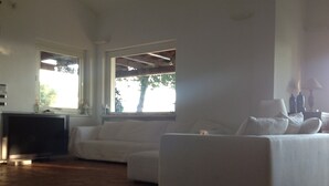 A spacious living area with a large window, a flat-screen TV, and a sofa. - LE QUERCE - Villa with spectacular sea view and swimming pool (Maratea)