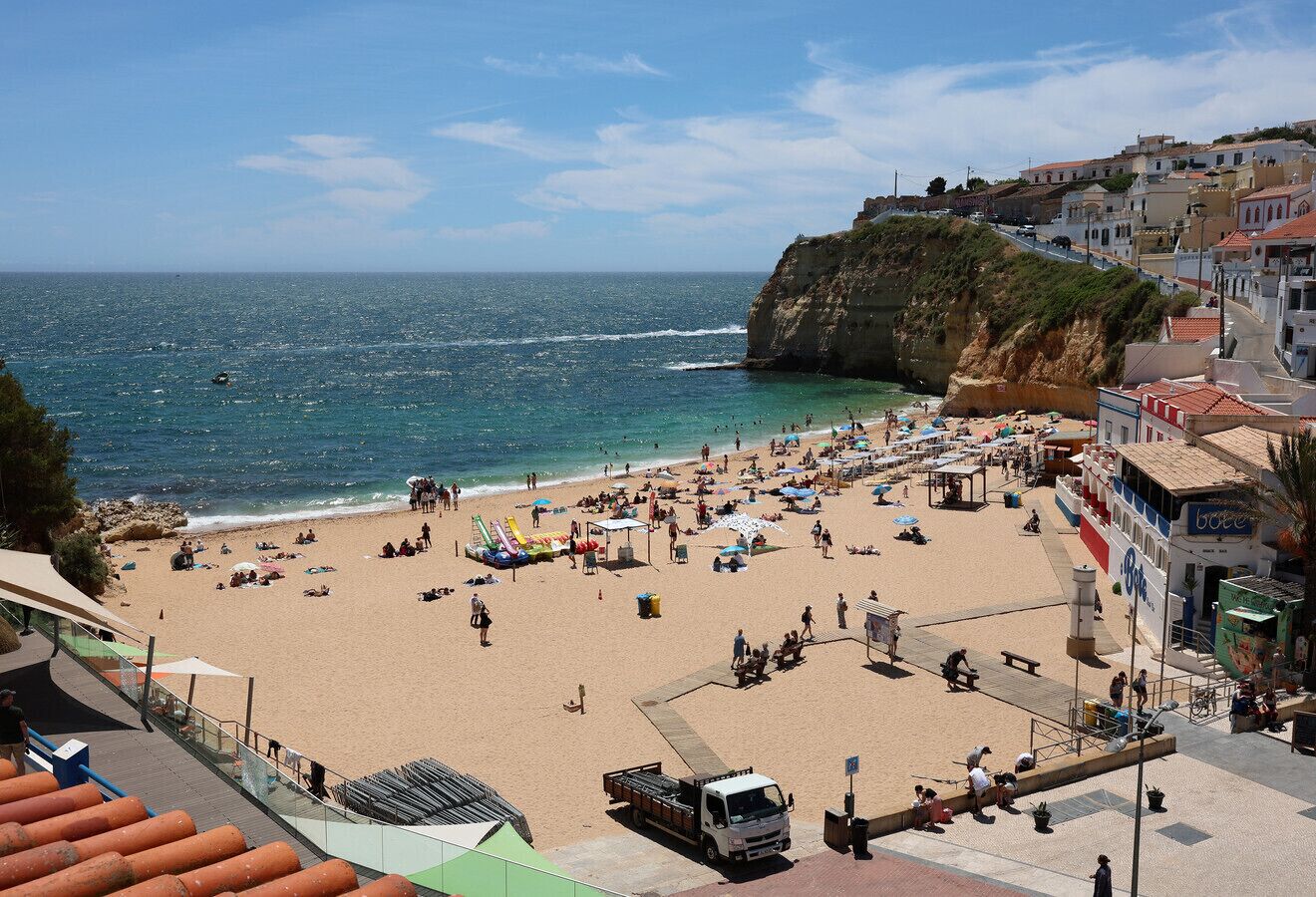 A beach with people, umbrellas, and a boat.
