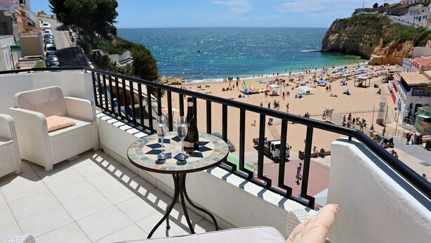A balcony with wicker furniture, a tiled floor, and a table with wine glasses.