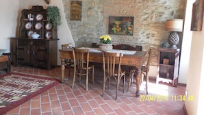 Un coin repas rustique avec un mur en pierre, des meubles en bois et un sol carrelé.