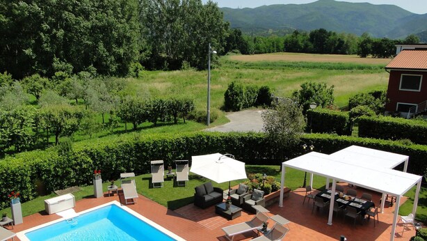 A swimming pool with lounge chairs and a covered patio area, surrounded by greenery and a view of distant hills. - Close to centre of Lucca. Perfect base for exploring. Exclusive use of pool, A/c (Lucca)
