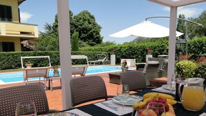 An outdoor dining area with a pool view, including tables, chairs, and a fruit platter. - Close to centre of Lucca. Perfect base for exploring. Exclusive use of pool, A/c (Lucca)