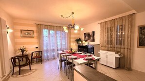 A dining area with a table set for four, a kitchen with a stove and cabinets, and a chandelier. - Close to centre of Lucca. Perfect base for exploring. Exclusive use of pool, A/c (Lucca)
