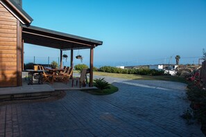 Un patio couvert aménagé avec du mobilier d’extérieur, une pergola et une vue sur le paysage environnant.