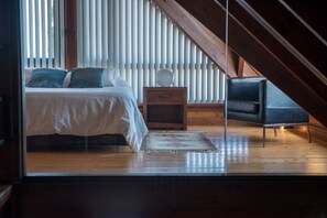 Une chambre à coucher avec un lit, une table de chevet, une chaise et une fenêtre avec des stores.