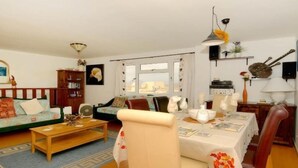 Una sala de estar acogedora con un sofá, una mesa de centro y una mesa de comedor preparada para dos personas.