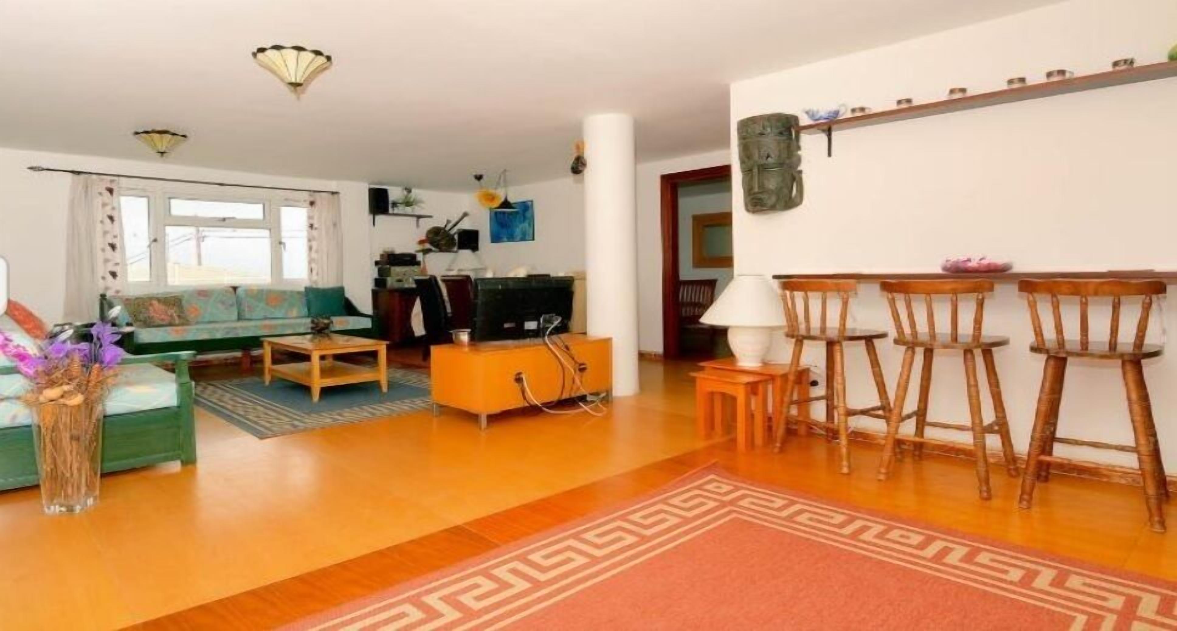 A living room with a sofa, coffee table, and a dining area with chairs.