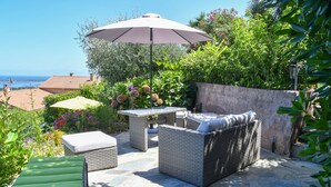Eine Terrasse im Freien mit Korbmöbeln, einem Tisch und einem Sonnenschirm.