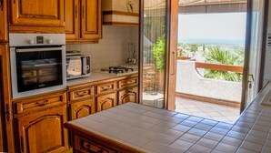 Eine Küche mit Holzausstattung, einem Bosch-Ofen, einem Toaster und Blick auf einen Balkon mit Terrasse.