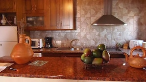 A kitchen with wooden cabinets, a stone backsplash, a coffee maker, a toaster, and a fruit bowl on the counter. - VILLA WITH SEA AND MOUNTAIN VIEWS, NEAREST BEACH 6KM (Almuñecar)