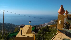 A coastal view with terracotta pots on a balcony, a clear sky, and a distant town. - VILLA WITH SEA AND MOUNTAIN VIEWS, NEAREST BEACH 6KM (Almuñecar)