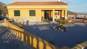 A yellow building with a tiled roof, stone foundation, and a gravel driveway. - VILLA WITH SEA AND MOUNTAIN VIEWS, NEAREST BEACH 6KM (Almuñecar)