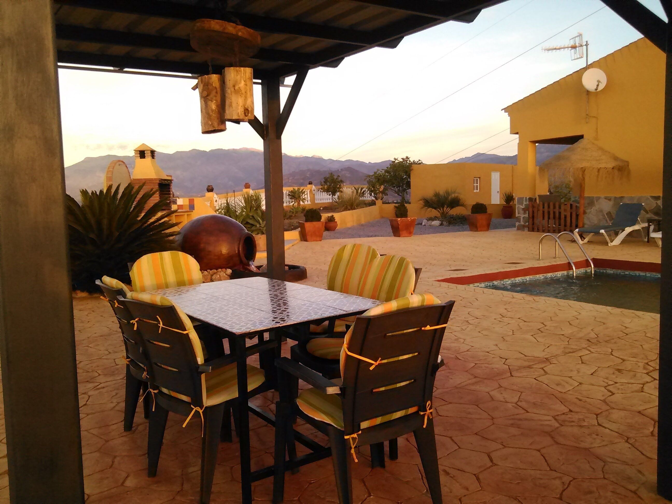 Eine Außenpatio mit Tisch und Stühlen, einem kleinen Pool und Blick auf Berge.