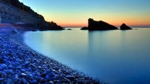 A calm beach with pebbles and a rocky outcrop in the distance. - Small house by the sea (refurbished October 2025) (Imperia)