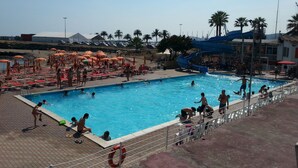 A swimming pool with multiple lanes, surrounded by sun loungers and umbrellas. - Small house by the sea (refurbished October 2025) (Imperia)
