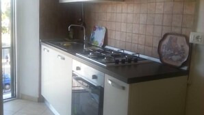 A kitchen with white cabinets, a stove, an oven, and a tiled backsplash. - Small house by the sea (refurbished October 2025) (Imperia)