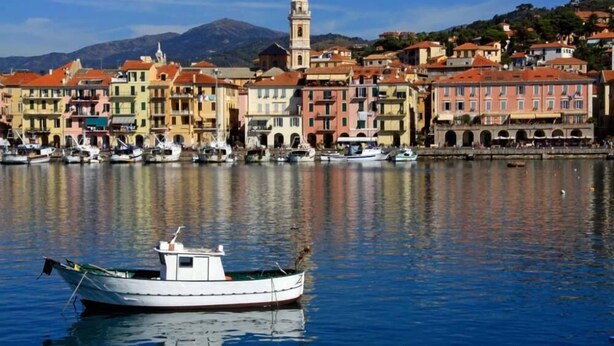 A waterfront town with colorful buildings, a prominent tower, and boats docked along the shore. - Small house by the sea (refurbished October 2025) (Imperia)