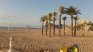 A beach with palm trees, a volleyball net, and a cityscape in the background. - APARTMENT WITH FANTASTIC VIEWS TO THE BEACH TO THE SEA AND TO THE RESIDENTIAL COMPLEX (Benidorm)