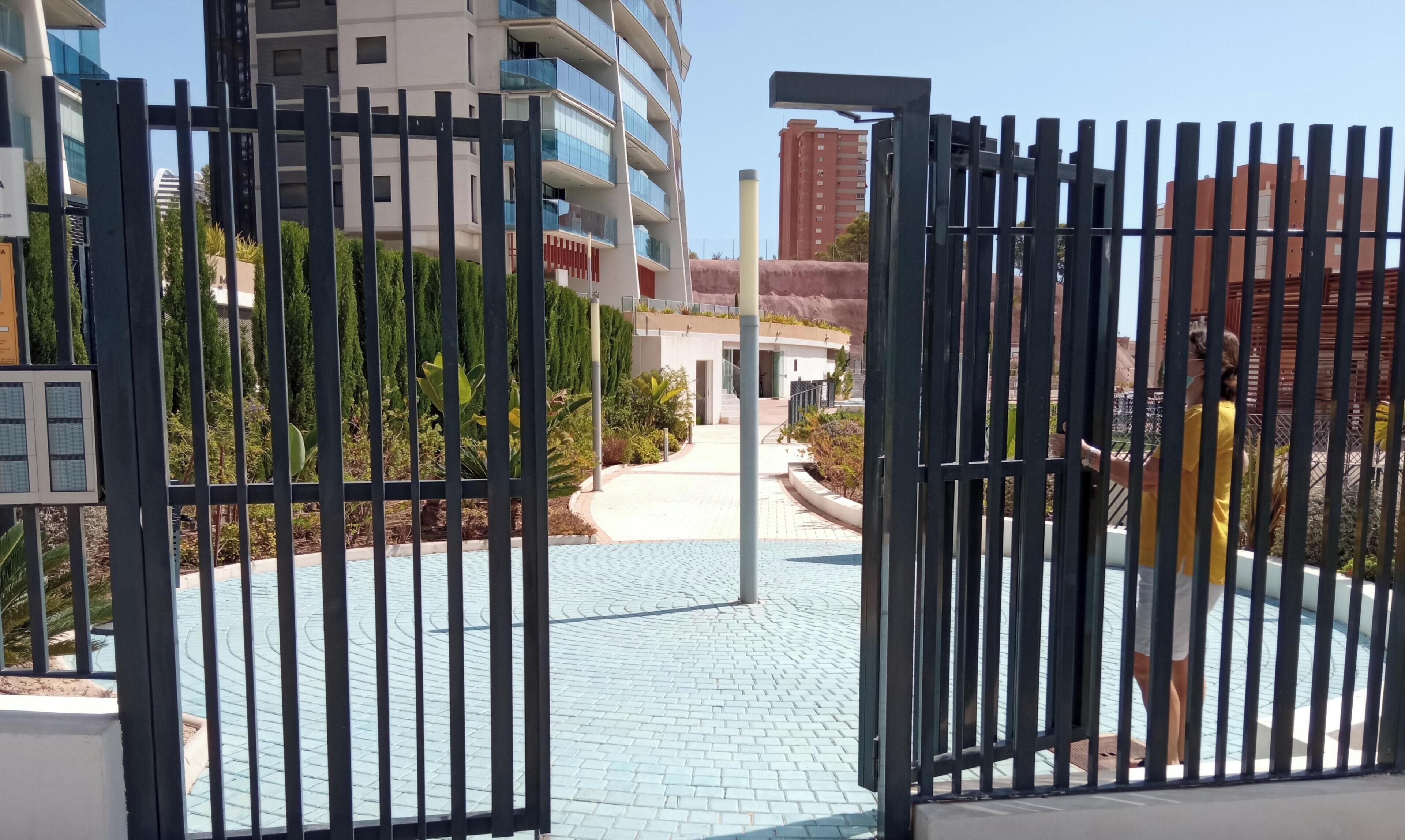 A gated entrance to a residential area with a paved pathway leading to a building.