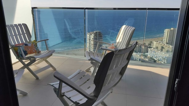 A balcony with two lounge chairs facing a cityscape and ocean view. - APARTMENT WITH FANTASTIC VIEWS TO THE BEACH TO THE SEA AND TO THE RESIDENTIAL COMPLEX (Benidorm)