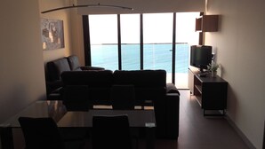 A living room with a sofa, a coffee table, and a TV on a stand. There is a large window with a view of the sea. - APARTMENT WITH FANTASTIC VIEWS TO THE BEACH TO THE SEA AND TO THE RESIDENTIAL COMPLEX (Benidorm)