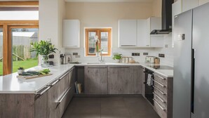 A modern kitchen with a central island, white cabinetry, and a stainless steel refrigerator. - Swallow's Orchard - Glastonbury (Glastonbury)