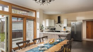 A modern kitchen with a dining area, large windows, and a view of the outdoors. - Swallow's Orchard - Glastonbury (Glastonbury)