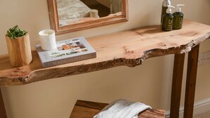 A wooden vanity with a book titled "MADE from LIVING," a white candle, and two bottles of lotion. - Swallow's Orchard - Glastonbury (Glastonbury)