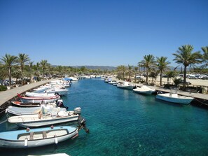 Eine Marina mit vertäuten Booten entlang eines klaren Wasserwegs, umgeben von Palmen und blauem Himmel.