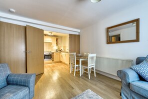 A modern apartment with a dining area, kitchen, and two sofas.