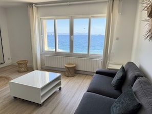 A living room with a view of the sea, a grey sofa, a white coffee table, and wicker stools. - Superb villa "feet in the water"  (Roquebrune-Sur-Argens)