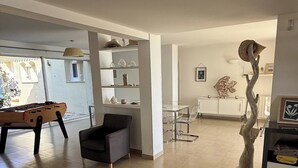 A spacious living area with a foosball table, a modern armchair, and a unique wooden sculpture. - Superb villa "feet in the water"  (Roquebrune-Sur-Argens)