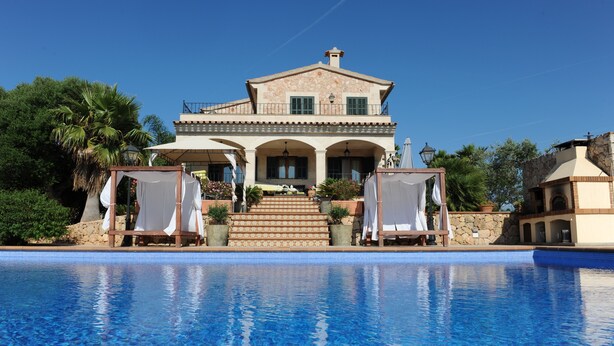 Un'ampia casa a due piani con una piscina di fronte.