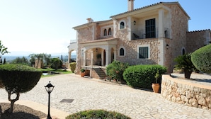 Una villa in pietra con facciata in pietra, diversi balconi e un vialetto lastricato.